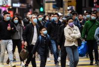 Foto ilustrasi:  Pejalan kaki yang memakai masker menyebrang jalan di Hongkong, China.  Subvarian Omicron BA.1.1 ditemukan di Suzhou, wilayah tetangga Shanghai yang kini memasuki fase lockdown kedua. Foto oleh Anthony WALLACE / AFP)